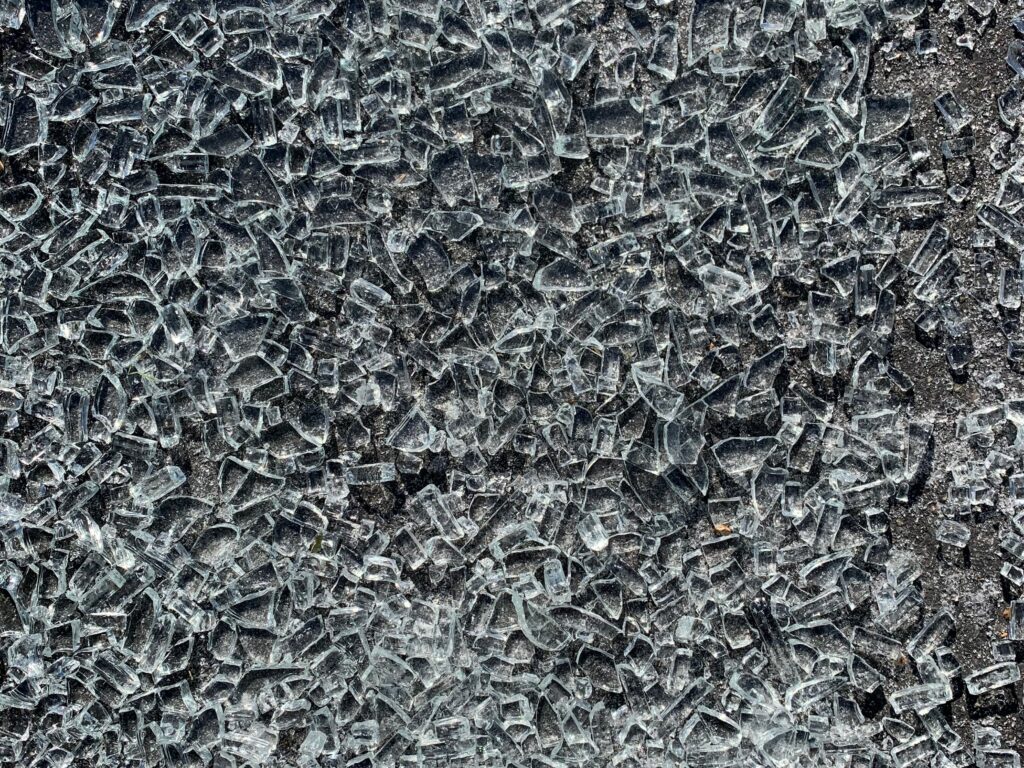 Hundreds of shards of broken glass on black asphalt