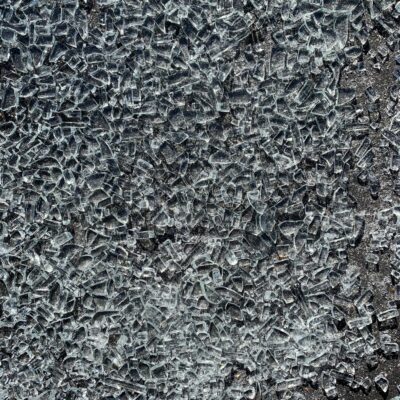 Hundreds of shards of broken glass on black asphalt