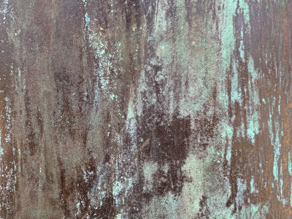 Grungy and corroded metal surface with teal like color ove red rust