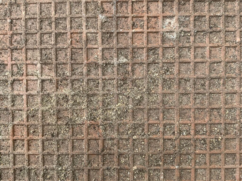 Rusty metal with square grid and dirt overlaying